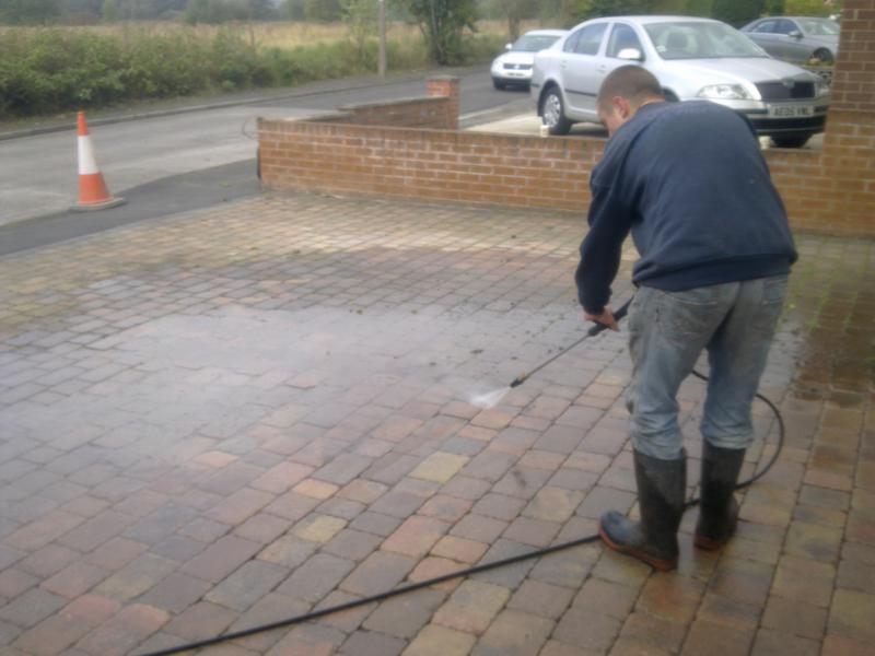 A Worsley Driveways crew member pressure washing an existing block paved driveway