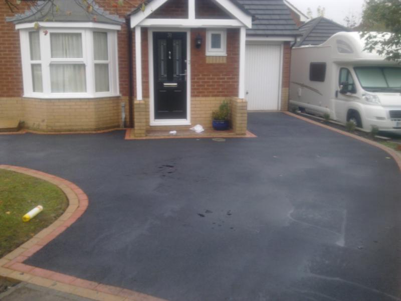 Tarmac driveway with a red block paved edging curve at a Walkden house